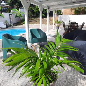 a patio with chairs and a plant next to a pool at Villa Lunéa in Sainte-Luce
