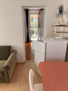 a kitchen with a refrigerator and a couch and a chair at Apartman Bari Petrcane in Petrcane