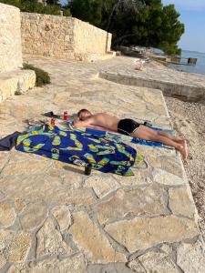 um homem deitado numa toalha na praia em Apartman Bari Petrcane em Petrcane