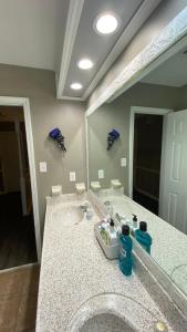 La salle de bains est pourvue d'un lavabo et d'un grand miroir. dans l'établissement Red Door North Jackson-Ridgeland Vacation Home, à Jackson