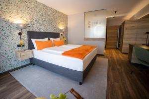 Schlafzimmer mit einem Bett mit orangefarbenen Kissen und einem Schreibtisch in der Unterkunft Lieb&Wert in Raesfeld
