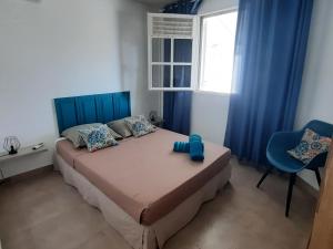 een slaapkamer met een bed met een blauw hoofdeinde en een raam bij Villa Lunéa in Sainte-Luce