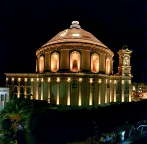 a building is lit up at night at TAFERNINE STUDIO in the heart of Mosta in Mosta