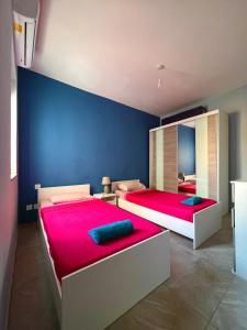 2 camas en un dormitorio con una pared azul en New Breeze en St Paul's Bay