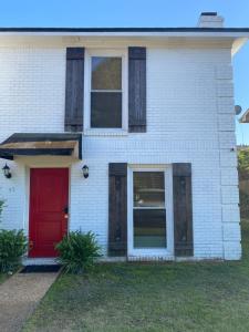 une maison en briques blanches avec une porte rouge dans l'établissement Red Door North Jackson-Ridgeland Vacation Home, à Jackson