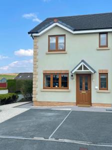 a white house with brown doors and a driveway at Number 1 Longstone Court in Haverfordwest