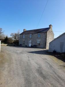 een oud stenen huis met een onverharde weg ervoor bij The Hollow in Tullow