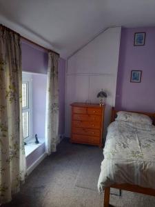a bedroom with a bed and a dresser and a window at The Hollow in Tullow