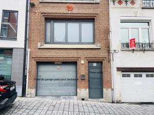 un bâtiment en briques avec deux portes de garage et un panneau sur celui-ci dans l'établissement Logements des choraux, à Tournai