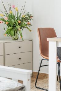 a white dresser with a vase of flowers next to a desk at Barrique - Somló Country Home in Somlóvásárhely