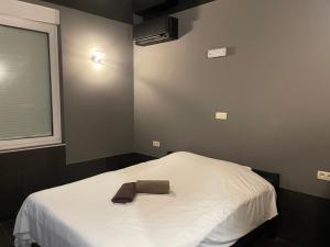 ein Schlafzimmer mit einem weißen Bett mit einer braunen Krawatte darauf in der Unterkunft Logements des choraux in Tournai