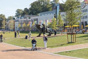 un grupo de personas en un parque con una estatua de dinosaurio en B&B Noviomagus en Nijmegen