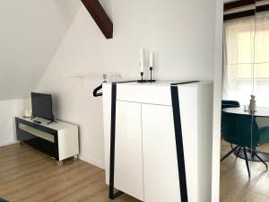 a room with a white cabinet and a desk with a television at CITYNA Apartment Bielefeld in Bielefeld