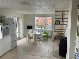 a kitchen and living room with a table and a staircase at Stor lys lejlighed med terrasse og altan in Helsingør