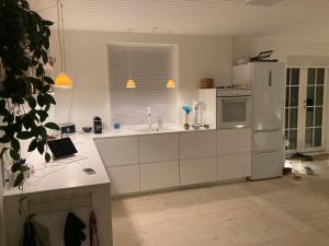  La cuisine est équipée de placards blancs et d'un réfrigérateur. dans l'établissement Stor lys lejlighed med terrasse og altan, à Elseneur