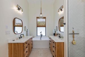 baño con 2 lavabos y bañera con 2 espejos en Sunset Rock at Lake Martin, en Alexander City