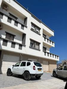un coche blanco estacionado frente a un edificio en Résidence Amel, en Aïn El Turk