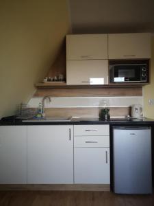 a kitchen with white cabinets and a microwave at Apartament z widokiem na góry in Ząb