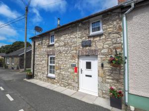 una casa de piedra con una puerta blanca y una calle en Y Bwthyn en Tal-gareg