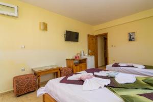 a room with two beds and a table and a television at Fener Guest House in Pomorie