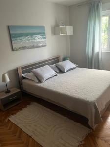 1 dormitorio con 1 cama grande con sábanas blancas y ventana en Apartment Frane, en Kaštela