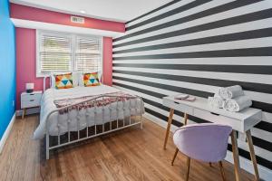 大西洋城Stylishly Renovated 5-Bedroom Home in AC - Perfect for Groups and Families的卧室设有条纹墙、一张床和一张书桌