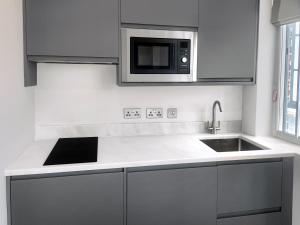 a kitchen with a sink and a microwave at Chelsea Flat 10 mins Harrods, Gym, Air Conditioning in London