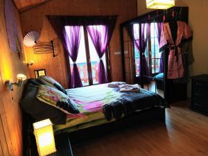 a bedroom with a bed with purple curtains and a window at Chez l'Eveline in Les Bois