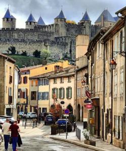 un grupo de personas caminando por una calle con un castillo en Les Florentines, en Carcassonne
