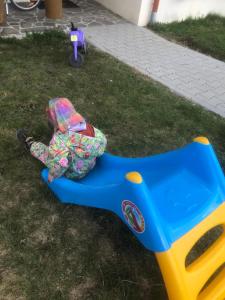 a child laying on a swing in the grass at Casa Bogát Ház in Harghita-Băi