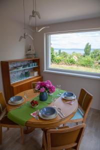 einem Esstisch mit Stühlen und einem Tisch mit Blumen darauf in der Unterkunft Turquoise Lake Guesthouse Balaton in Balatonszárszó