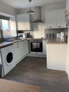 a kitchen with white cabinets and a washing machine at Stunning Apartment In The Heart of Broadway in Broadway