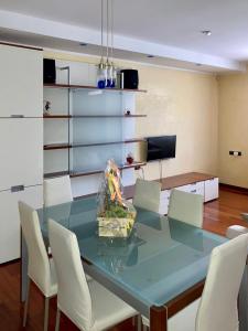 ein Esszimmer mit einem Glastisch und weißen Stühlen in der Unterkunft Chilli House in Sottomarina