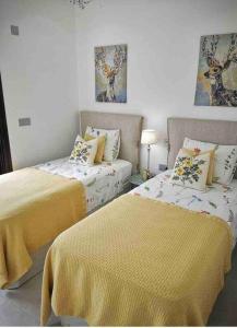 una camera con due letti con lenzuola gialle di Bahia Homes Torrevieja a Torrevieja