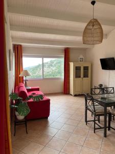 ein Wohnzimmer mit einem roten Sofa und einem Tisch in der Unterkunft Hameau de pietra longa Salvini PORTO-VECCHIO in Sotta