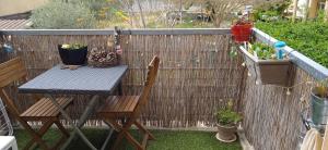 une table, deux chaises et une clôture avec des plantes dans l'établissement Superbe appartement lumineux au sud d Orange, à Orange