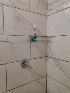a white tiled shower with a toothbrush on a wall at Comfort place 2 in Pretoria