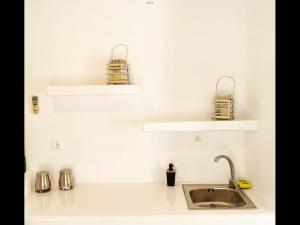 a kitchen counter with two shelves and a sink at Amarielia's Studios in Tinos