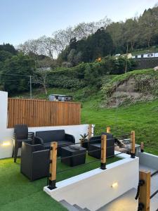 a patio with couches and chairs on the grass at B&C Furnas House in Furnas