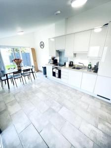 a kitchen with white cabinets and a table and chairs at 2 Bedroom Modern House in Cambridge city centre in Chesterton