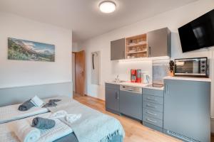 a bedroom with a bed and a kitchen with a microwave at Ferienwohnung Wendelstein in Kiefersfelden
