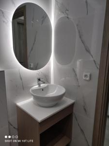 W łazience znajduje się biała umywalka i lustro. w obiekcie Yannis Apartments w miejscowości Amoudara