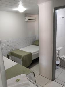 Habitación pequeña con 2 camas y espejo. en Pousada Aracaju, en Aracaju
