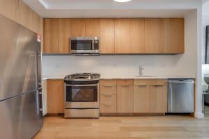 eine Küche mit Küchengeräten aus Edelstahl und Holzschränken in der Unterkunft Global Luxury Suites at Via 57 in New York