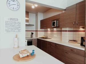 une cuisine avec des placards en bois et une horloge murale dans l'établissement Cozy 2 bedroom apartment - metro Montgomery, à Bruxelles