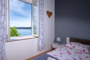 Schlafzimmer mit einem Fenster mit Blick auf das Wasser in der Unterkunft Apartment Dobrić in Koromačno