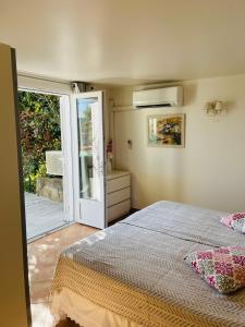 a bedroom with a bed and a sliding glass door at Hameau de pietra longa Salvini PORTO-VECCHIO in Sotta