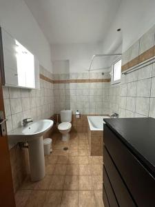 La salle de bains est pourvue d'un lavabo, de toilettes et d'une baignoire. dans l'établissement Central appartment3 with parking, à Larissa