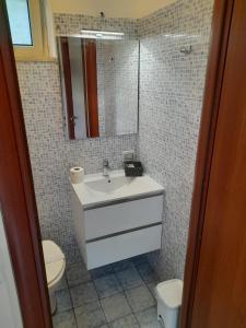 Un baño con lavabo, inodoro y espejo. en SUMMER HOUSE AL MARE, en Gaeta