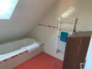 bagno bianco con vasca e pavimento rosso di Maison familiale entre Beauval & Chambord a Pruniers